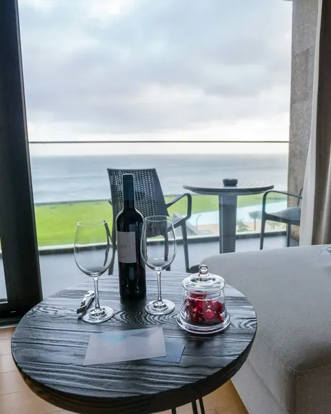 Table de balcon face à l’océan, deux verres et une bouteille