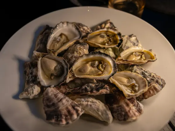 Huîtres ouvertes sur une grande assiette, dans la pénombre
