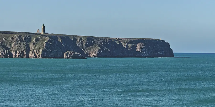 Une île aux falaises sombres et son phare, posée sur la mer bleue